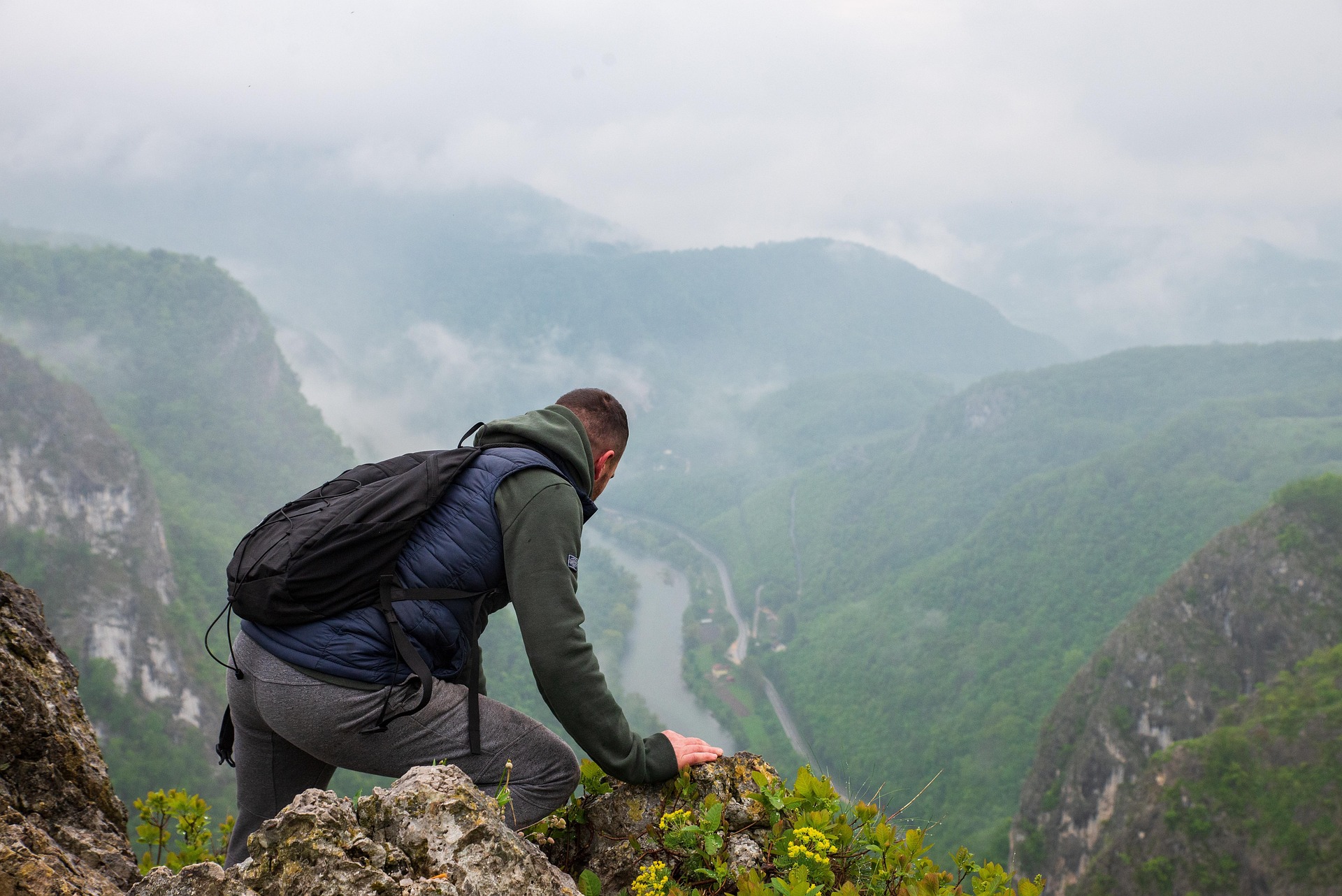 Man hiking a mountain side overlooking a valley
